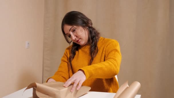 Mujer morena envolviendo regalo en papel kraft en cámara lenta — Vídeos de Stock