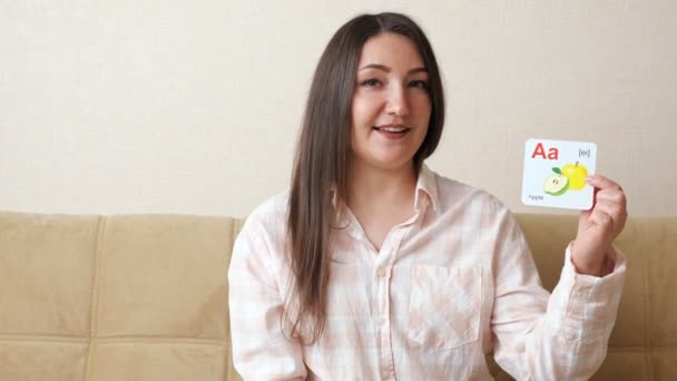 Kobieta demonstruje pocztówki z literami alfabetu angielskiego i wymawia dźwięki i słowa — Wideo stockowe