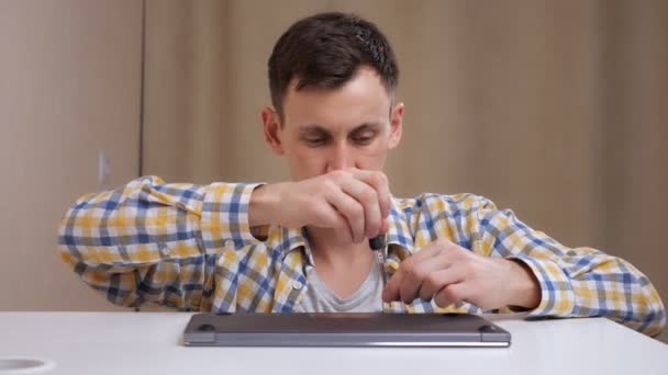 Mand demonterer bærbar computer med skruetrækker derhjemme – Stock-video