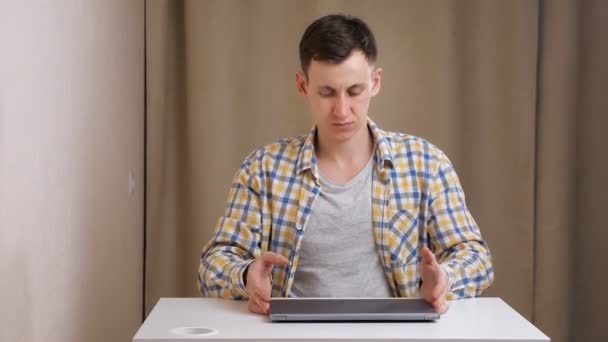 Young man opens laptop and starts typing while sitting at table — Stock Video
