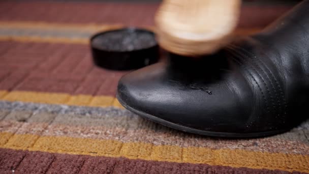 Close-up of a shoe brush rubbing a black boot — Stock Video