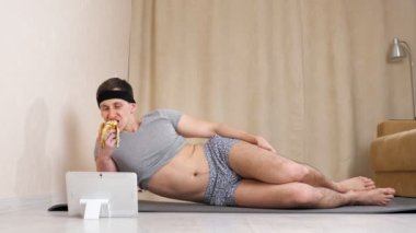 Kadın adam muz yiyor ve yerde yatarken tablete bakıyor.