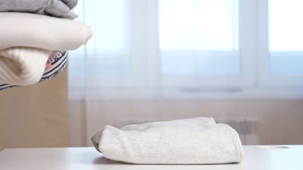 Empregada doméstica coloca roupas de malha dobradas limpas na mesa branca — Vídeo de Stock