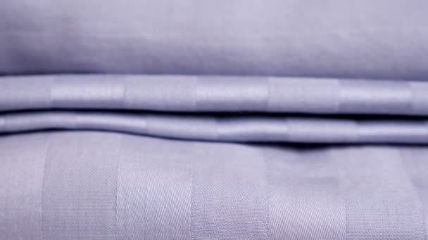Movimiento hacia abajo a lo largo de la pila de ropa de cama limpia púrpura en la mesa blanca — Vídeos de Stock