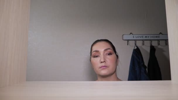 Hemmafru med hår bulle lägger vikta rena kläder på hyllan — Stockvideo