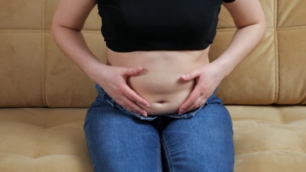 Mujer irreconocible tocando la grasa del vientre mientras está sentado en el sofá — Vídeos de Stock