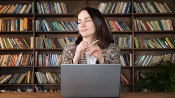 Zamyšlená brunetka v bundě přes bílou blůzu drží pero — Stock video