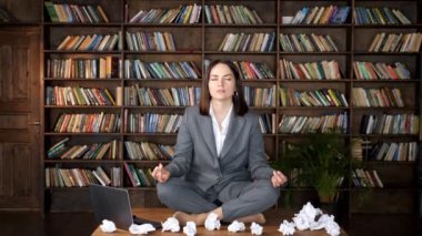 Kısa saçlı iş kadını yoga pozisyonunda meditasyon yapıyor.