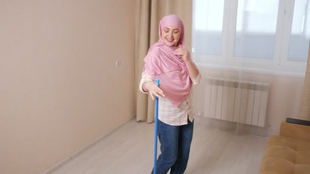 Junge muslimische Frau wäscht den Boden und tanzt mit einem Wischmopp in Zeitlupe — Stockvideo