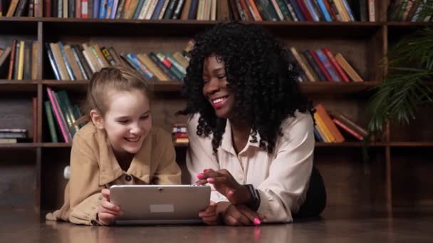 Schoolgirl dan babysitter melihat tampilan tablet dan tertawa — Stok Video