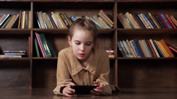 Ενδιαφερόμενη μαθήτρια παίζει online παιχνίδι σε μαύρο smartphone — Αρχείο Βίντεο