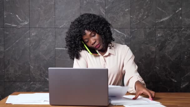 Woman manager explains via smartphone and looks at papers — Stock Video