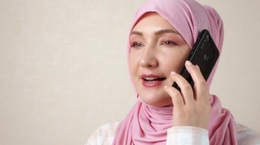 Genç, beyaz, Müslüman bir kadın telefonda konuşuyor.