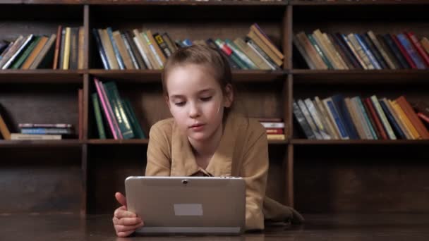Zaujalo vás školačka hraje online hru na tabletu v knihovně — Stock video