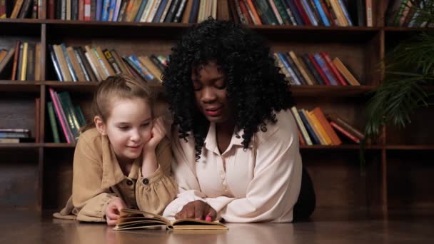 Afro-Amerikalı üvey anne ve sarışın kız peri masalı okuyorlar. — Stok video