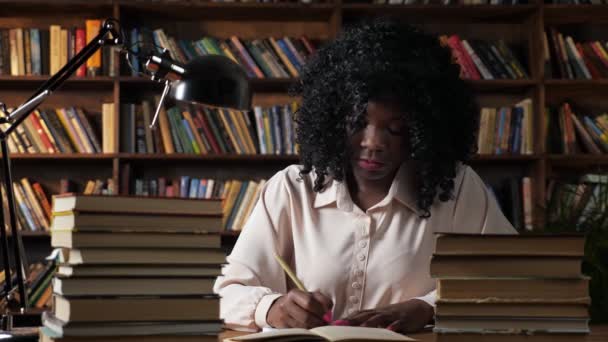 Donna afro-americana scrive nel taccuino in biblioteca pubblica — Video Stock