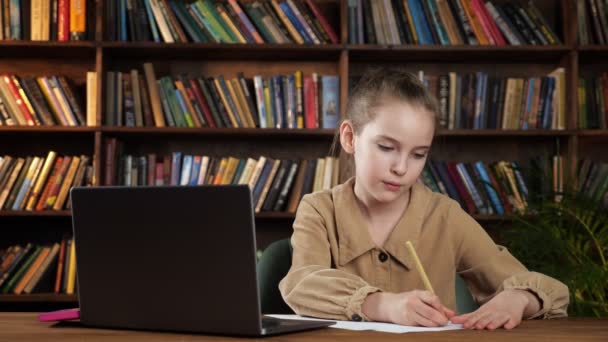 Poważna dziewczyna w brązowej kurtce pisze esej i papier łzy — Wideo stockowe
