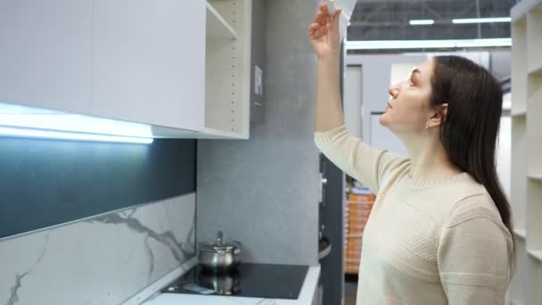 Mladá žena při pohledu na show kuchyně v obchodě — Stock video