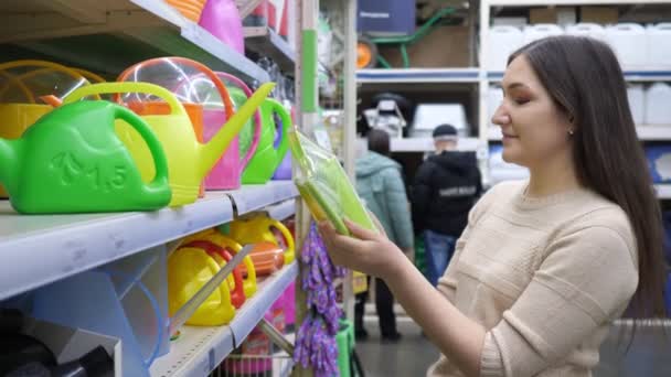 Jonge vrouw kiest een gieter in de winkel — Stockvideo