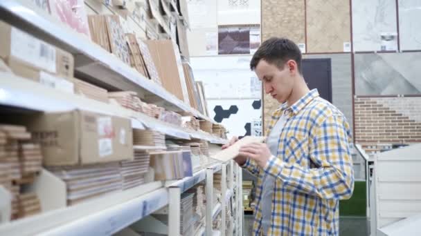 Молодий чоловік вибирає плитку в магазині обладнання — стокове відео