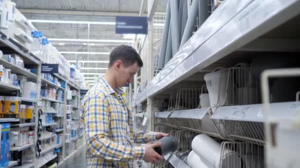 Joven elige una tubería de alcantarillado en una tienda especializada — Vídeos de Stock
