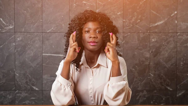 Worried black lady holds crossed fingers of trembling hands — Stock Photo, Image