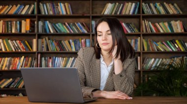 Kısa saçlı sıkıcı esmer dizüstü bilgisayar ekranına bakıyor.