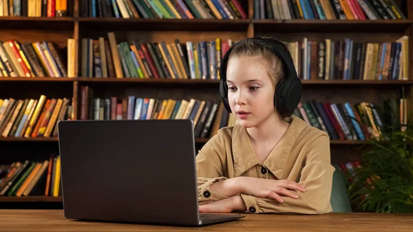 Lady junior student i svarta hörlurar lyssnar på lärare — Stockfoto