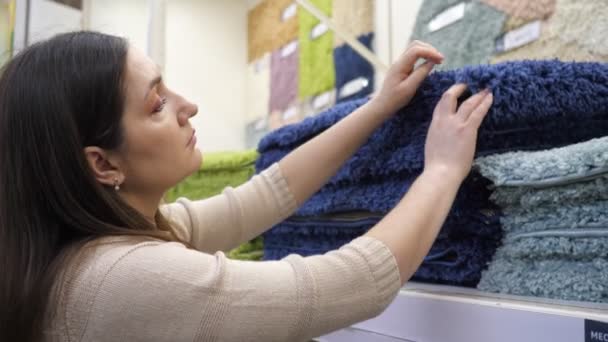 Mujer joven elige alfombra azul shaggy en la tienda — Vídeos de Stock