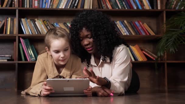 Dame noire parle à l'écolière avec tablette et montre des photos — Video