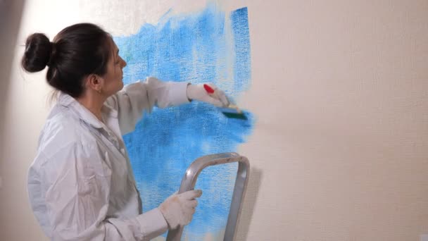 Vrouw professionele schilder in handschoenen schildert nieuwe platte muur — Stockvideo