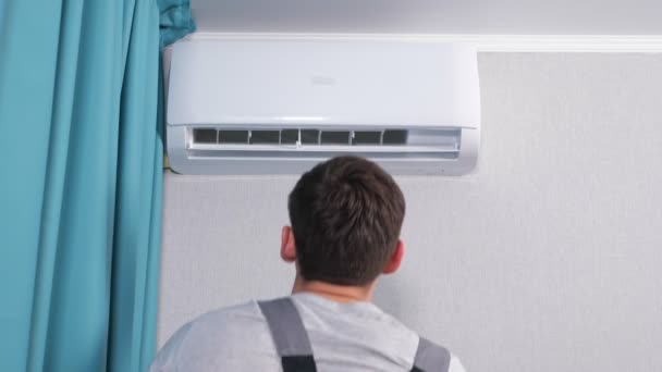 Mann im grauen T-Shirt öffnet Deckel einer Klimaanlage — Stockvideo