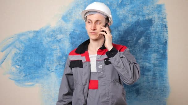 Reparador enfocado en casque habla con el empleador por teléfono — Vídeo de stock
