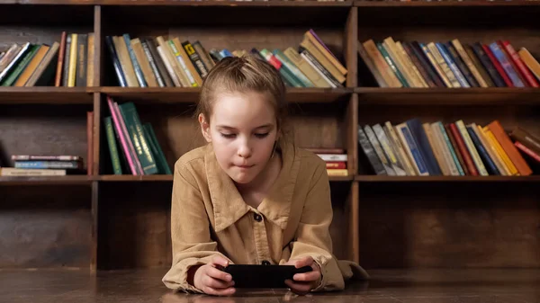 관심있는 여학생 이 검은 스마트폰으로 온라인 게임을 한다 — 스톡 사진