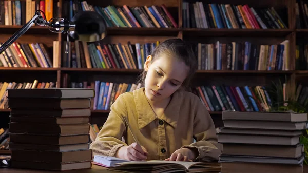 ジャケットに集中した女の子はノートブックで宿題を書きます — ストック写真