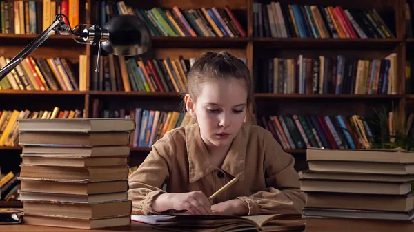 Kahverengi ceketli yorgun genç bayan kitaptan bir şeyler yazıyor. — Stok fotoğraf