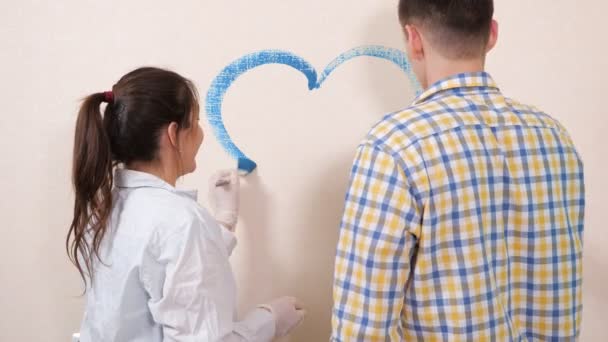 Couple romantique amoureux attire coeur avec de la peinture bleue sur le mur — Video