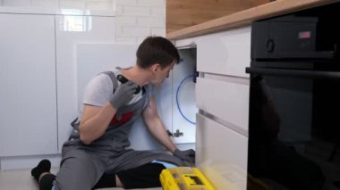 El feneri ustası lavabonun altındaki boruları inceliyor.