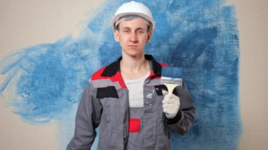 Tulum giyen işçi fırçayı tutar ve onay jesti gösterir