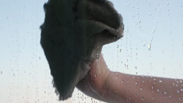 Onherkenbare vrouw wast het raam, close-up van waterdruppels op glas — Stockvideo