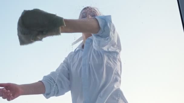 Eşarplı ve gömlekli bir kadın pencereyi paçavrayla yıkıyor. — Stok video