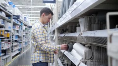 Genç adam özel bir dükkandaki kanalizasyon borularını karşılaştırıyor.