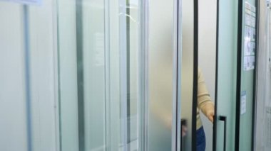 Kadın, buzlu cam ve siyah buzlu profiliyle duş kabinini inceliyor.