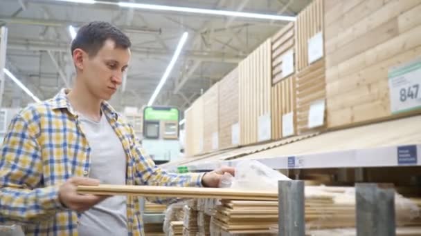 Jongeman kiest voor houten planken in een bouwmateriaalwinkel — Stockvideo