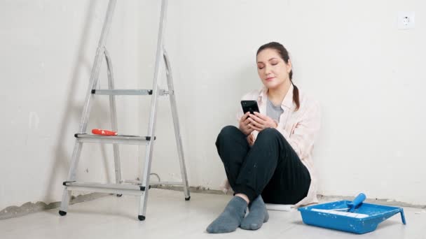 Designer senta-se perto de bandeja de pintura de parede vazia e escada de metal — Vídeo de Stock