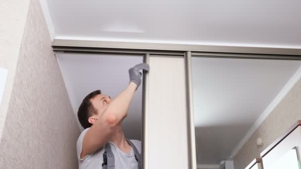 Workman dalam seragam memperbaiki kayu pintu geser lemari pakaian — Stok Video