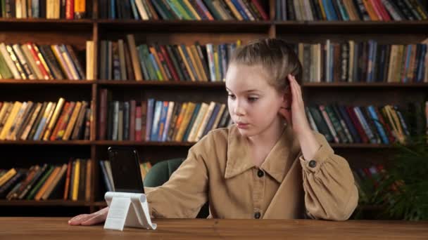 재킷을 입은 즐거운 여학생 이 스마트폰을 통해 친구들에게 이야기하는 모습 — 비디오