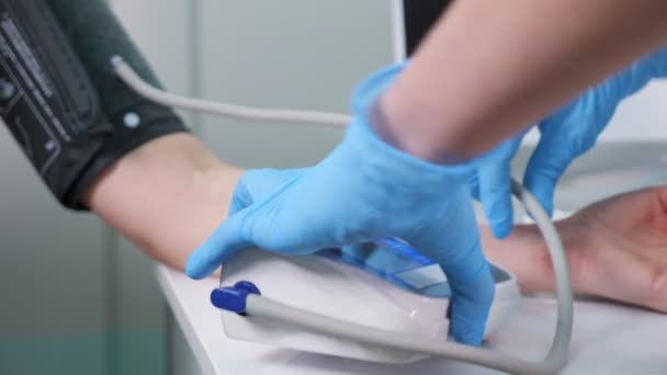 Enfermera pone manguito en el brazo del hombre para medir la presión en el hospital — Vídeos de Stock