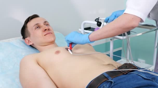 Медсестра кладе електроди на пацієнта людини, щоб зробити електрокардіограму — стокове відео