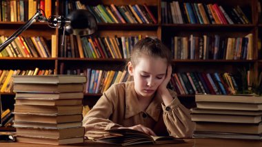 Kahverengi ceketli genç bayan kitaptaki eğitim materyallerini okuyor.